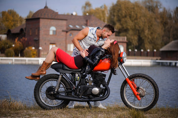 Naklejka na ściany i meble stylish and trendy couple in love on a lying motorcycle flirting close-up on a background of late autumn in the park