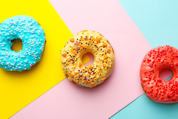 Tasty donuts with sprinkles on color background
