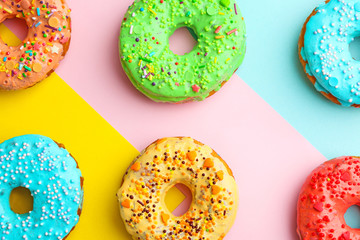 Tasty donuts with sprinkles on color background