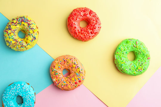 Tasty donuts with sprinkles on color background
