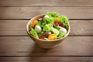 Bowl with delicious vegetable salad on wooden background