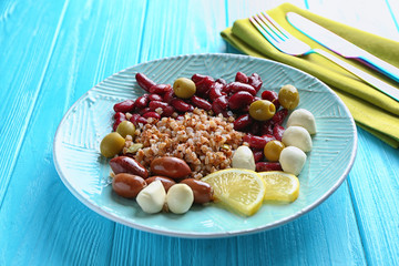Plate with buckwheat porridge, beans and mozzarella on table