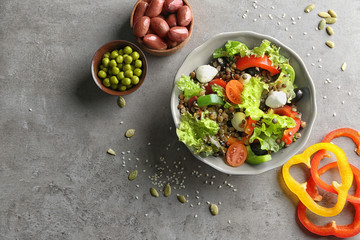 Bowl with delicious vegetables salad on grey background, top view