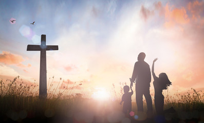 Family worship concept: Silhouette father mother and son looking for the cross on autumn sunrise background. - obrazy, fototapety, plakaty
