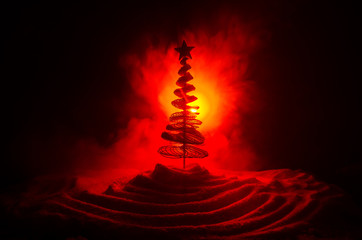 Christmas background with snowy fir tree. Snow Covered Christmas Tree stands out brightly against the dark red tones of this snow covered scene. Toned dark background