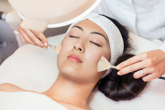 Close-up of the face of a beautiful young Asian woman relaxing during rejuvenating facial massage with brushes in a contemporary beauty center