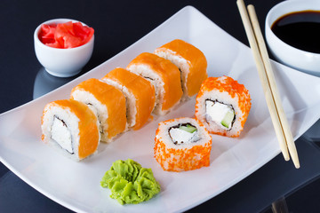 Various kinds of sushi served on black background.