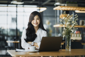 Beautiful happy young curly woman sitting in cafe and using laptop	