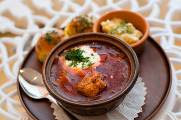 Ukrainian national cuisine, red borsch with meat and sour cream in a brown clay bowl