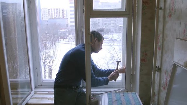 Man repairs wood window. Replace broken glass on window