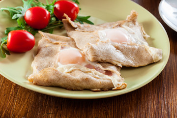 Fototapeta na wymiar Crepes with ham, cheese and poached egg on a plate