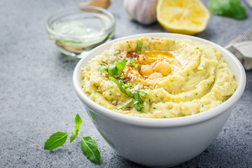 Classic chickpea hummus in a bowl on stone or concrete background. Selective focus, close up, copy space.