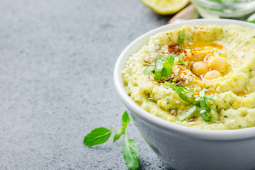 Healthy vegan chickpea hummus in a bowl on stone or concrete background. Selective focus, copy space. 