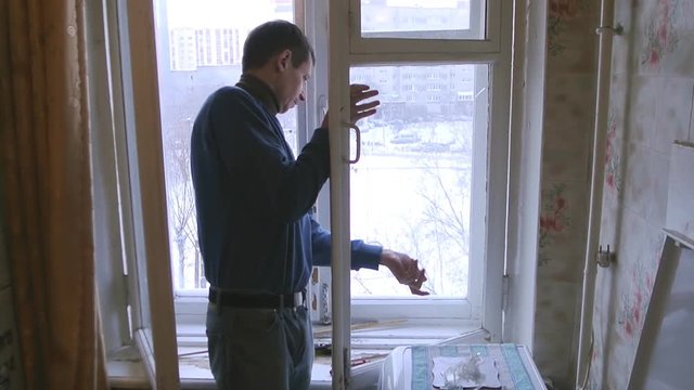 Man repairs wood window. Replace broken glass on window