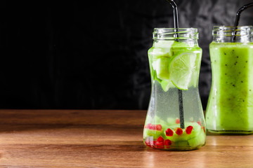 Refreshing drink from kiwi, green apple, lime, mint and pomegranate on a wooden table. The concept of a healthy diet, detox.