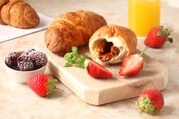 croissants with chocolate cream and berries strawberries on a light background