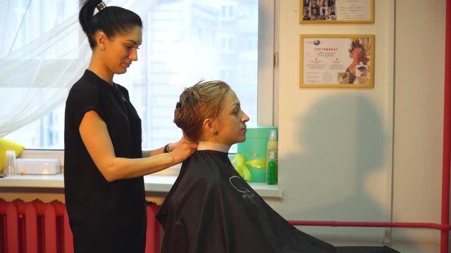 the hairdresser prepares the girl for a haircut