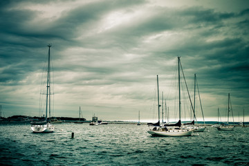 Nautical scene of anchored sailboats under storm clouds