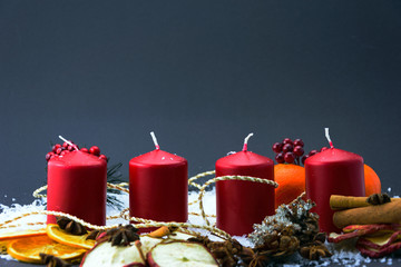 Advent candles as part of christmas ornament containing cinnamon, dried orange and apple slices, snow and anise.