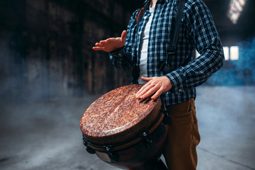 Male drummer playing on wooden drum