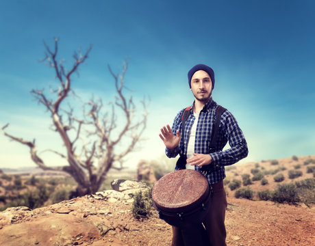 Drummer plays on wooden bongo drums in desert