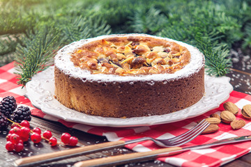 Homemade Christmas or New Year holiday berry pie with nuts on wooden table background. Concept of festive desserts