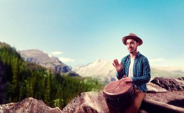Drummer with wooden drums plays on top of mountain