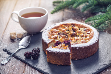 Homemade Christmas or New Year holiday berry pie with nuts on wooden table background. Concept of festive desserts