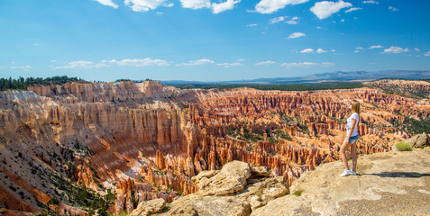 Beautiful girl sitting at the edge of the Bryce Canyon cliff in Arizona.