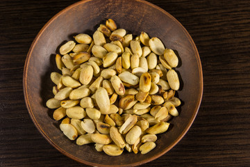 Roasted salted peanuts in plate on wooden table