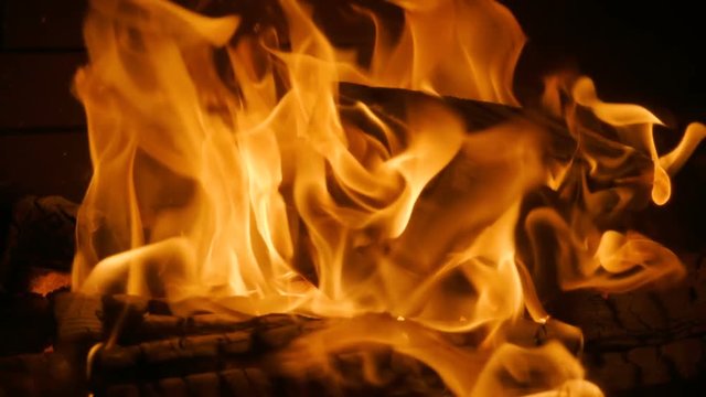 Close-up shot of warm cozy burning fire in a brick fireplace. Slow motion. HD