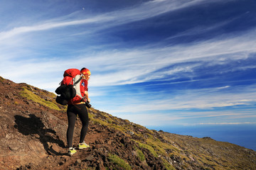 Young girl trekking and taking photos on Pico volcano (2351m) on Pico Island, Azores, Portugal,...