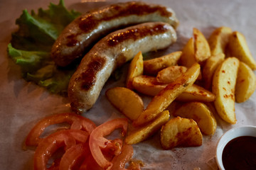 Hearty, fatty dish to the table. Beer. German national cuisine. Fried sausages with fried potatoes and sauce