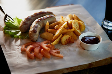 Hearty, fatty dish to the table. Beer. German national cuisine. Fried sausages with fried potatoes and sauce
