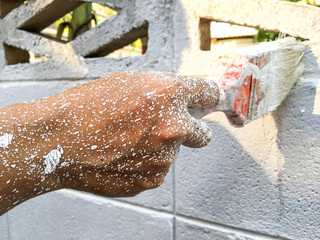 Woman's hand using paintbrush with white paint on wall, Stained  hand