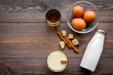 Make eggnog classic recipe. Eggs, milk, cinnamon, whiskey on dark wooden background top view copyspace