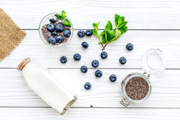 Naklejka na ściany i meble Eat chia seeds for breakfast with yogurt, blueberry and mint. White wooden background top view
