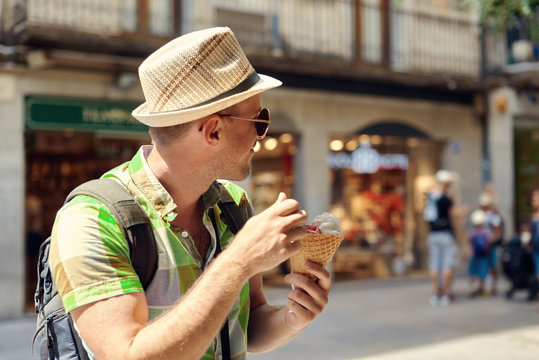 Short Bearded Man Enjoying Ice Cream Cone In A Town Street.