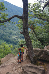 Naklejka premium Mom and little son tourists are looking from the high mountain to the view below