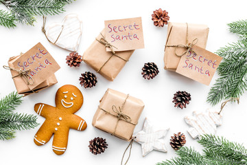 Christmas traditions. Gift boxes with notes Santa Secret near spruce branch and gingerbread cookies on white background top view