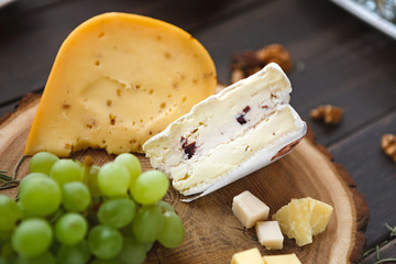 Cheese platter, parmesan on natural wood disc with grapes and nuts