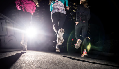 Three women running in the night in the city center
