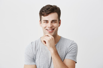Happy smiling young man demonstrates positive emotions or feelings, has trendy hairdo, dressed...