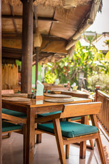 Fototapeta na wymiar Interior of a tropical restaurant on Bali island, Indonesia. Wooden table and chairs.