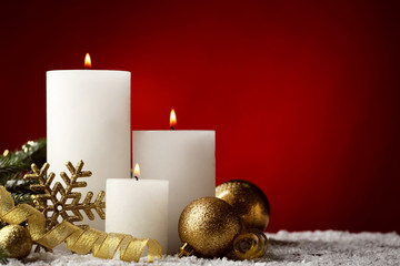 Christmas candles with baubles and snowflake on red background
