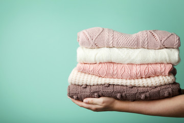 Female hands holding stack of knitted sweaters