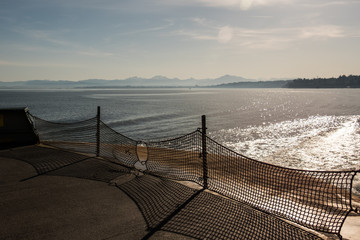 Sunrise over Puget Sound (water) and the Cascade Mountains with sun flare from a ferry deck