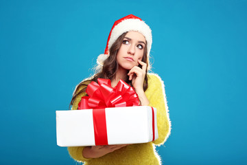 Beautiful young girl holding gift box on blue background