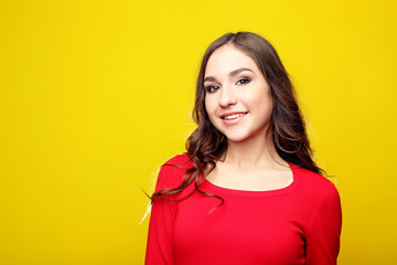 Beautiful young girl in red dress on yellow background