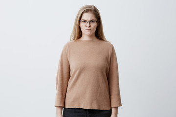 Aggravated blonde female with straight hair, wears spectacles, frowns face in discontent, feels...